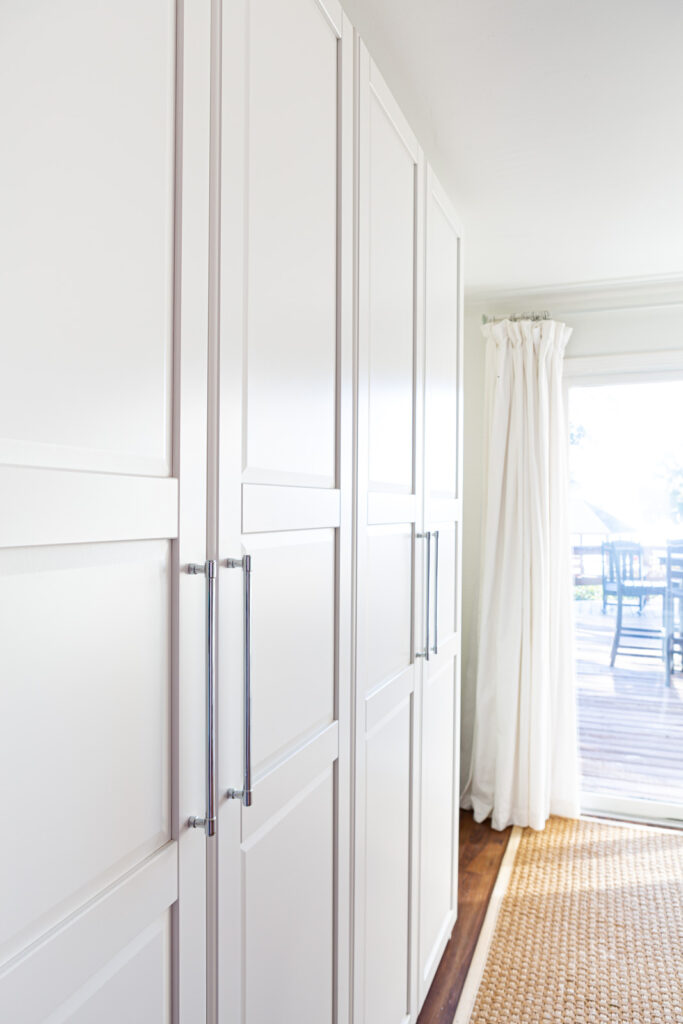 View of two side-by-side IKEA PAX storage units in white in a multi-purpose room in a home.