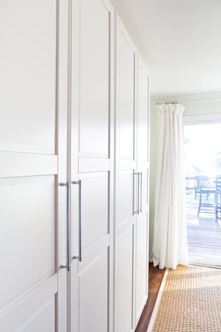 View of two side-by-side IKEA PAX storage units in white in a multi-purpose room in a home.