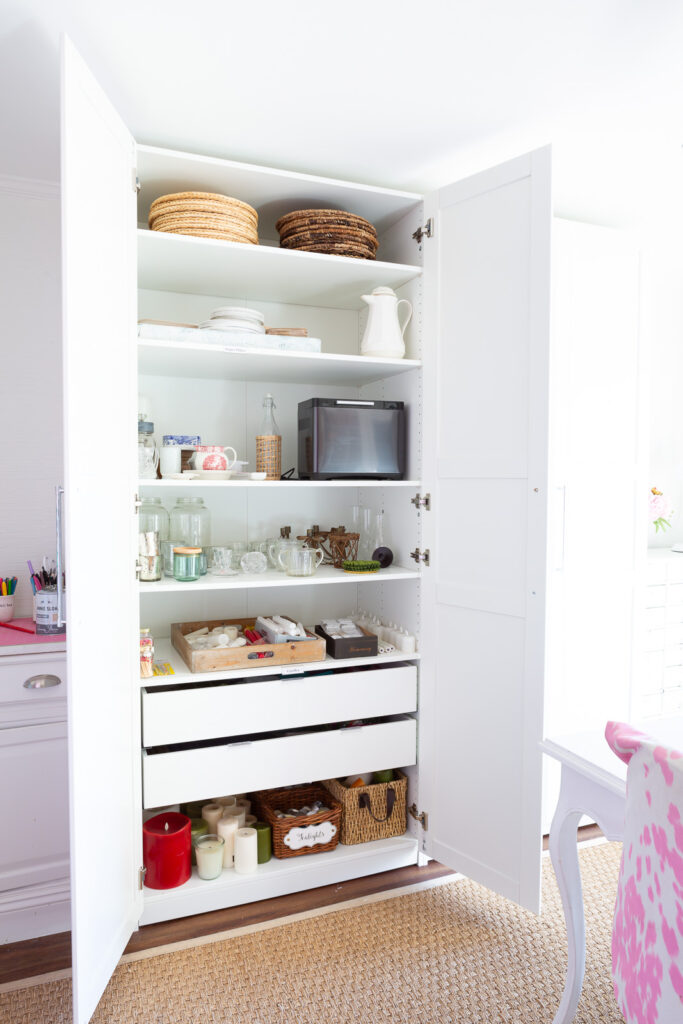 IKEA PAX storage closet in white fitted with shelves and 2 drawers.