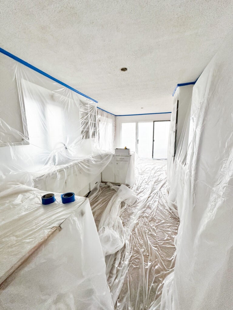 masking with plastic sheeting kitchen cabinets and floor to prepare to remove the popcorn ceiling in the room