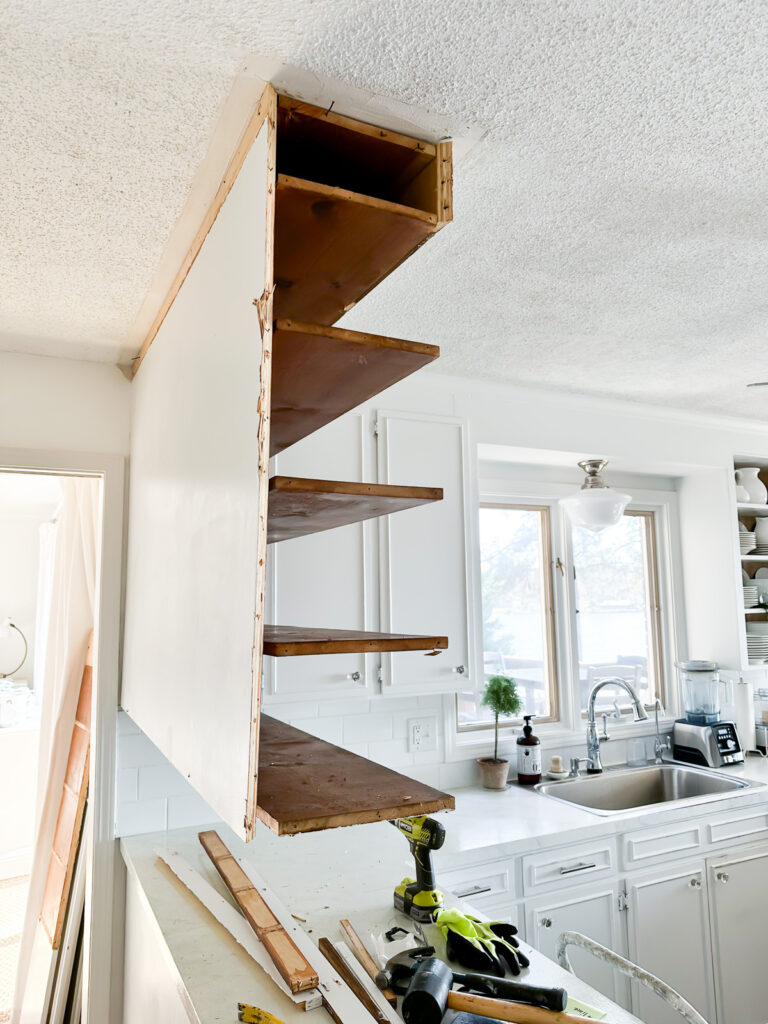 side view of kitchen cabinets hanging from ceiling after part of it has been removed.