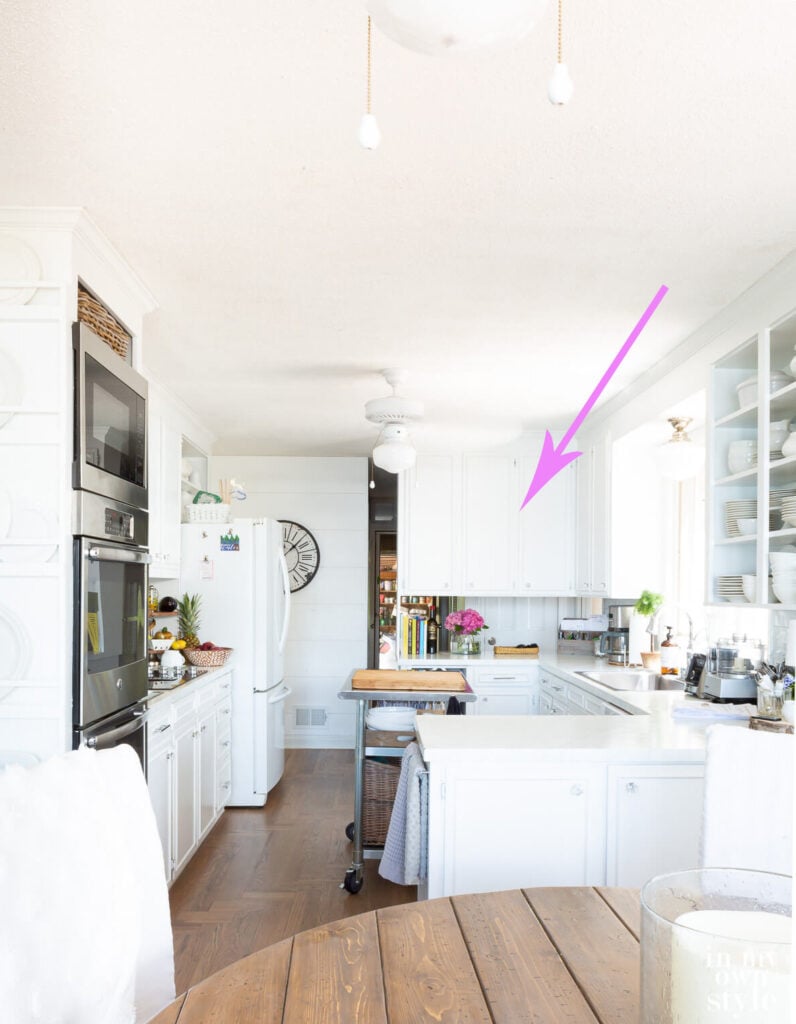 arrow pointing to section of upper wall cabinets in a small kitchen that are going to be removed.