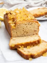 Vegan lemon and ginger drizzle cake on a sheet of baking paper with a couple of slices cut.