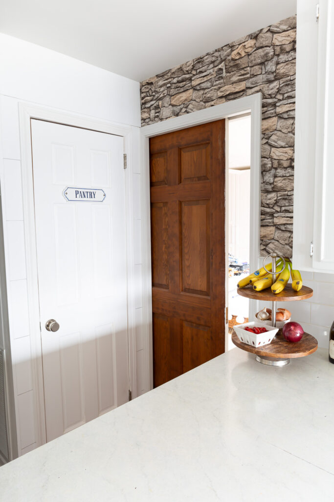 Looking at accent wall covered in faux stone wallpaper and a pocket door.