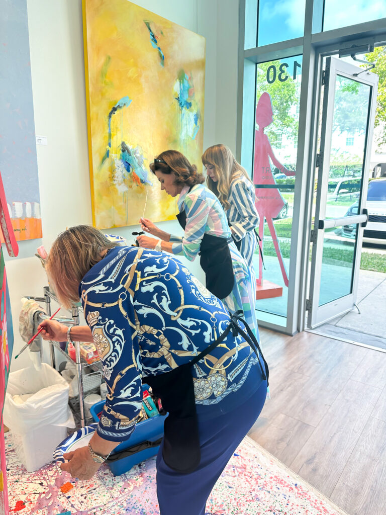 women painting a paper doll sculpture at a charity event at an Art Gallery.