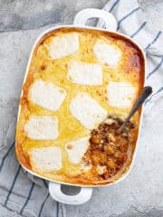 Cheesy vegan gnocchi bake in a white lasagna dish with a spoonful removed.