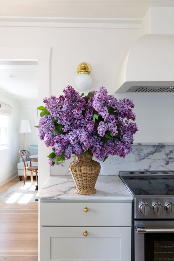 lilacs in a wicker vase in a kitchen counter