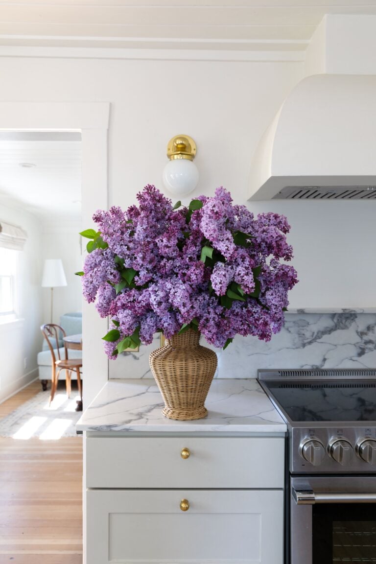 lilacs in a wicker vase in a kitchen counter