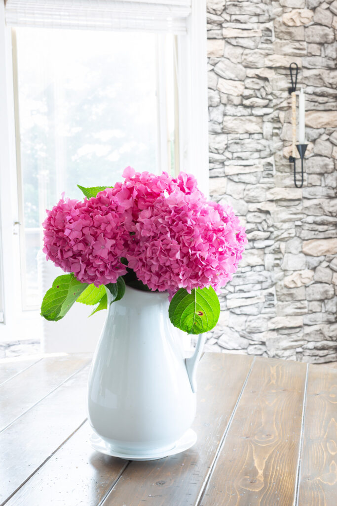 pink hydrangeas in a white pitcher on a table