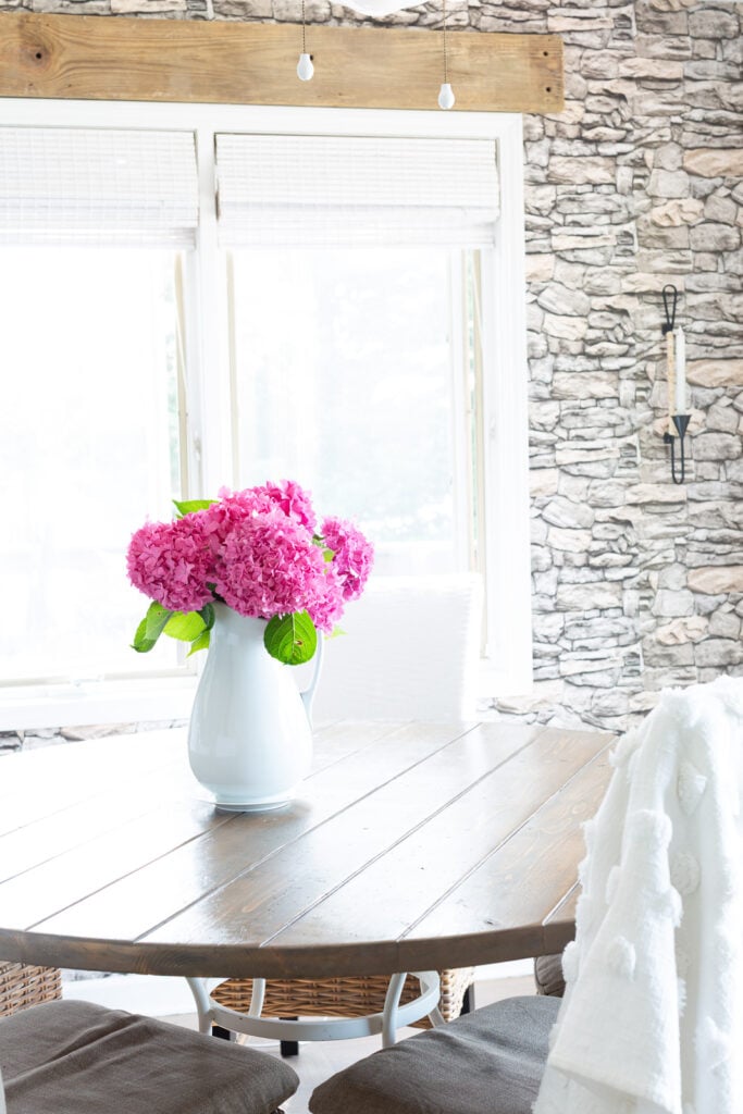pink hydrangeas in a white pitcher on a wood kitchen table