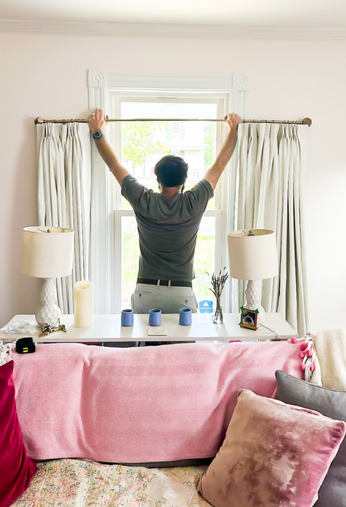 man hoisting up curtain rod with new TwoPages drapes attached.