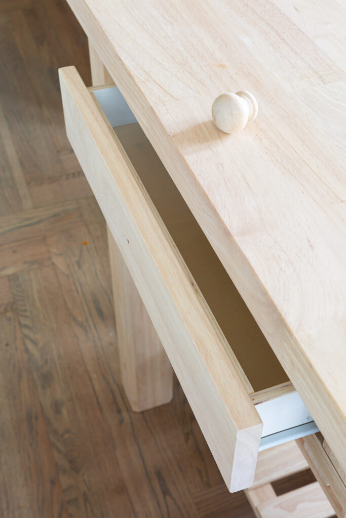 close up of wood drawer in wood kitchen island before getting painted with Sherwin Williams Emerald paint.