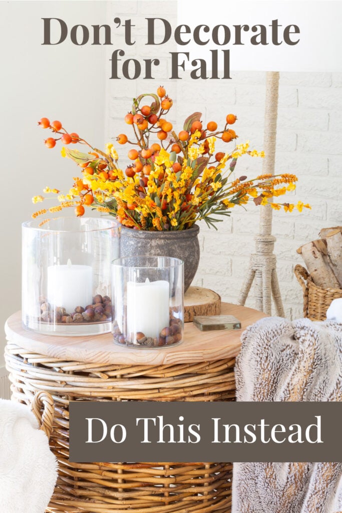 Fall flowers and candles on a wicker table. Text overlay says - Don't decorate for fall, do this instead.