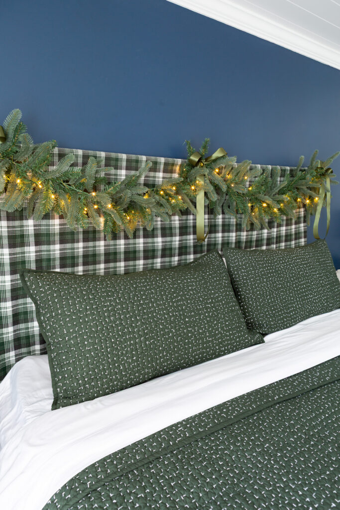 Bed headboard decorated for Christmas with a King of Christmas Noble Fir garland