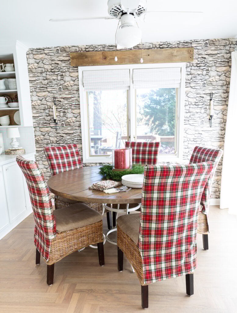 Looking at a round dining table where all the chairs are covered in a classic red and white Christmas plaid fabric.
