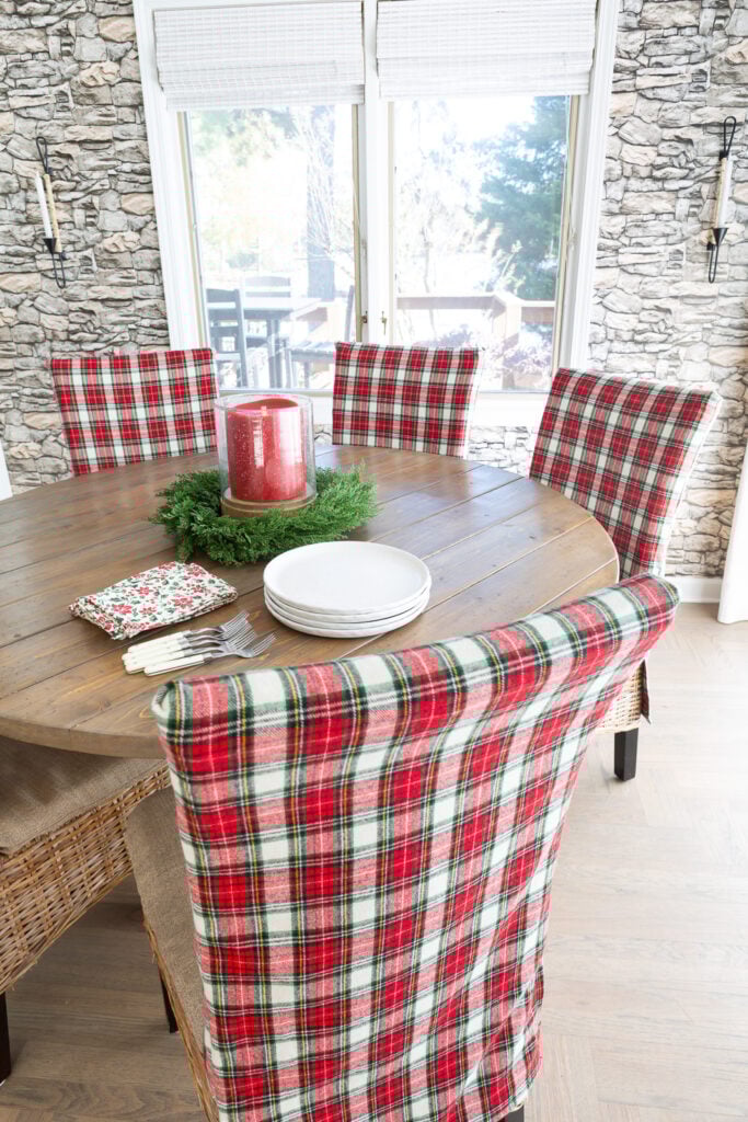Looking down at a round dining table where all the chairs are covered in a classic red and white Christmas plaid fabric.