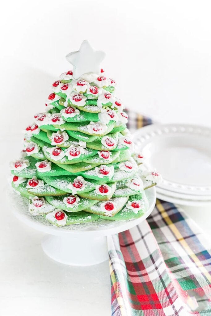 Christmas cookie tree made using cookie cutters. Plaid dishtowel next to it.