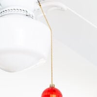 a red Christmas ornament added to the pull chain of a ceiling fan.