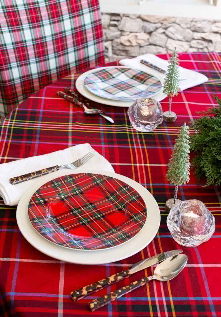 A dining table set for Christmas using a red plaid and green theme.