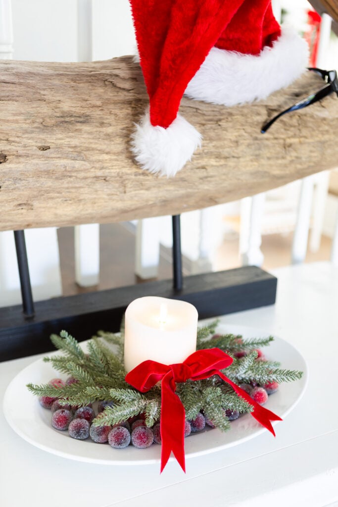 a white oval platter filled with sugared cranberries a wreath, white candle and red velvet bow.