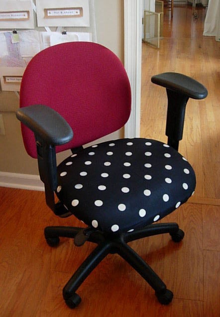 White and black polka dot fabric being added to a red office chair.